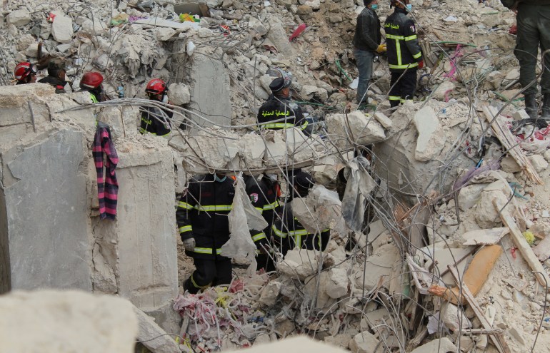 Des membres de l'équipe de secours algérienne recherchent des survivants sur le site d'un bâtiment endommagé, au lendemain du séisme d'Alep
