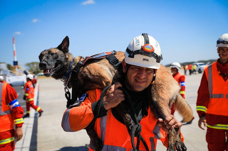 A member of El Salvador's Urban Search And Rescue Team (USAR) carry a rescue dog