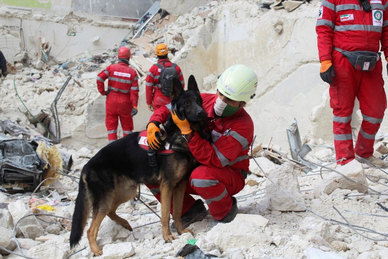 A member of the Iranian rescue team holds a rescue dog as he stands on rubble of a damaged building, in the aftermath of the earthquake in Aleppo, Syria February 10, 2023. REUTERS/Firas Makdesi TPX IMAGES OF THE DAY
