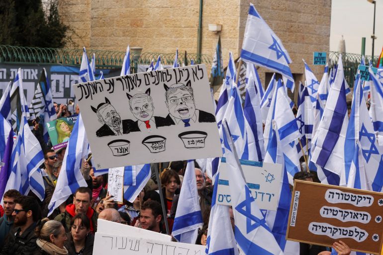 Israelis hold flags and posters as they demonstrate against the government's plan to overhaul judicial powers
