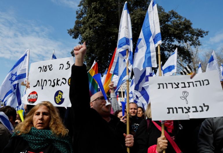 Israelis hold flags and posters as they demonstrate on the day Israel's constitution committee is set to start voting on changes that would give politicians more power on selecting judges while limiting Supreme Court's powers to strike down legislation, outside the Knesset, Israel's parliament in Jerusalem, February 13, 2023.