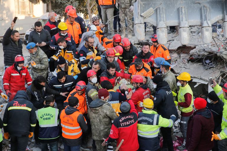 Dozens of rescue workers are massed around a survivor at the site of a crumbled building.