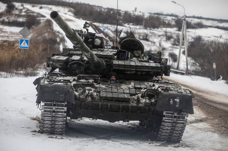 A Ukrainian serviceman drives a tank along a road outside the frontline town of Bakhmut,