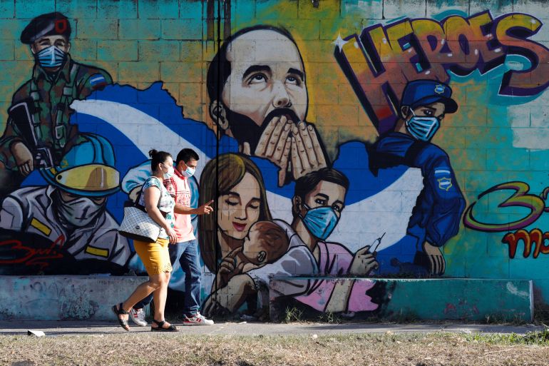 People walk by graffiti of Salvadoran President Nayib Bukele