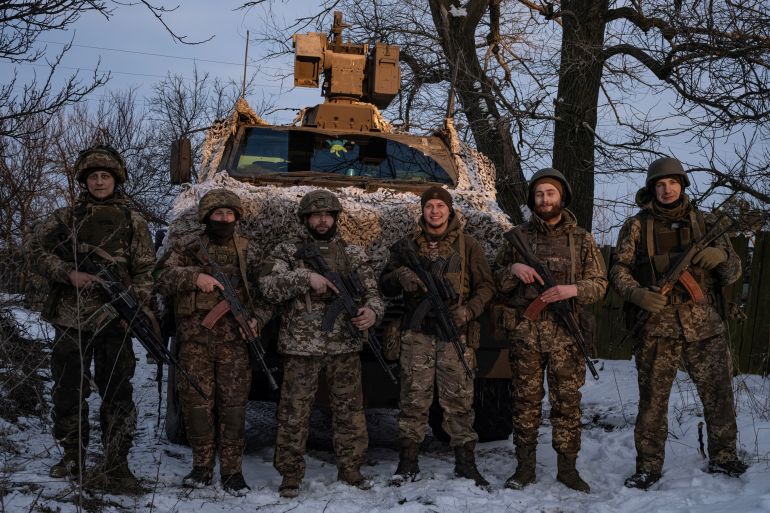 Ukrainian servicemen stand in front of a Bushmaster Protected Mobility Vehicle near Bakhmut