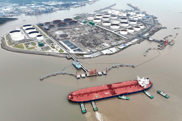 An aerial view shows tugboats helping a crude oil tanker to berth at an oil terminal, off Waidiao Island in Zhoushan, Zhejiang province, China.