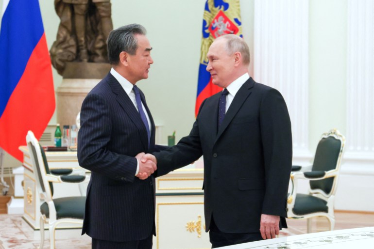 Russia's President Vladimir Putin shakes hands with China's Director of the Office of the Central Foreign Affairs Commission Wang Yi