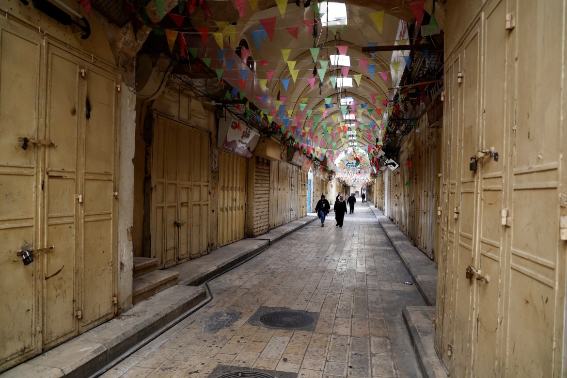 Palestinians walk past closed shops during a strike