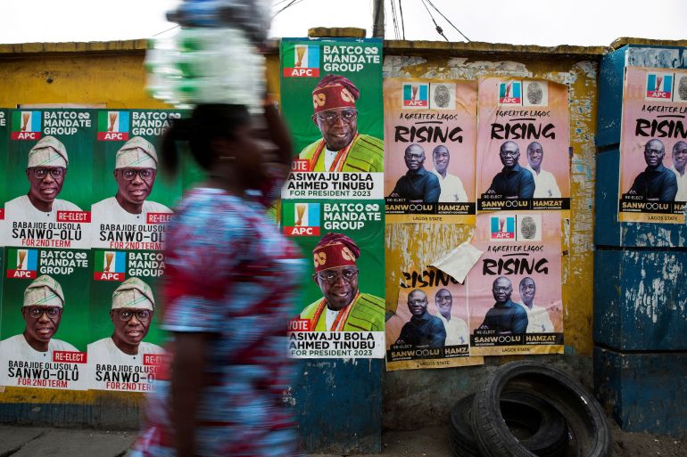 FILE PHOTO: A woman walks past election posters of APC party candidates including presidential hopeful Bola Ahmed Tinubu in Lagos, Nigeria on February 24, 2023. REUTERS/James Oatway/File Photo