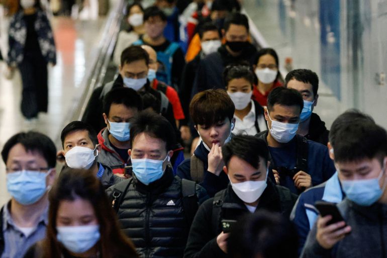 A crowd of men and women in a metro station in Hong Kong. They are all wearing face masks.