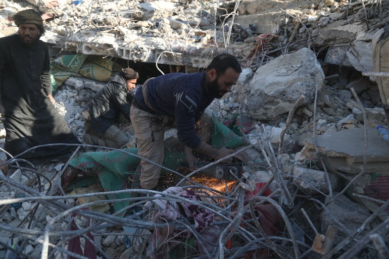A Syrian man looks through the rubble of a collapsed building following a devastating earthquake in the town of Jenderez in northwestern Syria