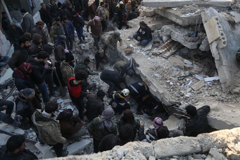 Civil defence teams working to rescue people trapped under collapsed buildings in Syrian town of Jenderez
