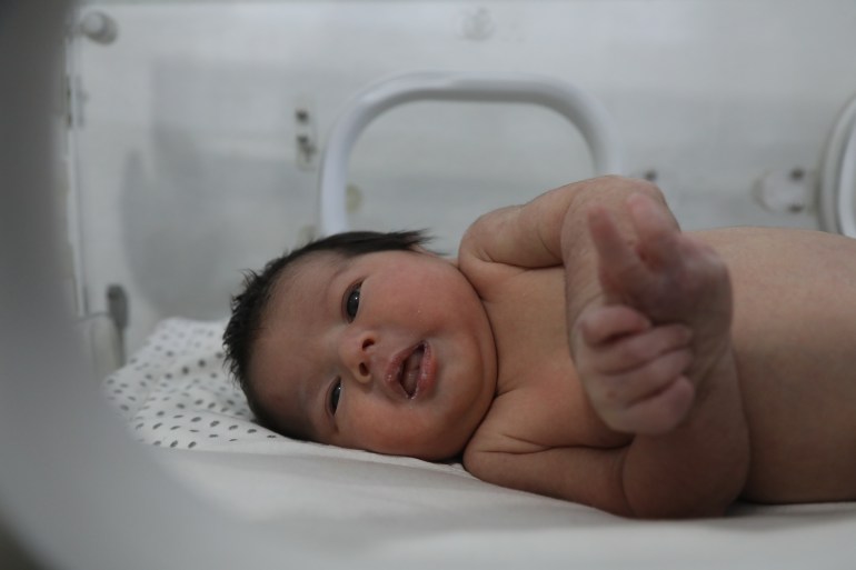 Baby Aya looks from the incubator to the photographer