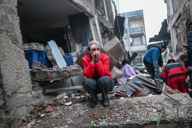An earthquake survivor reacts as rescuers look for victims and other survivors in Hatay.