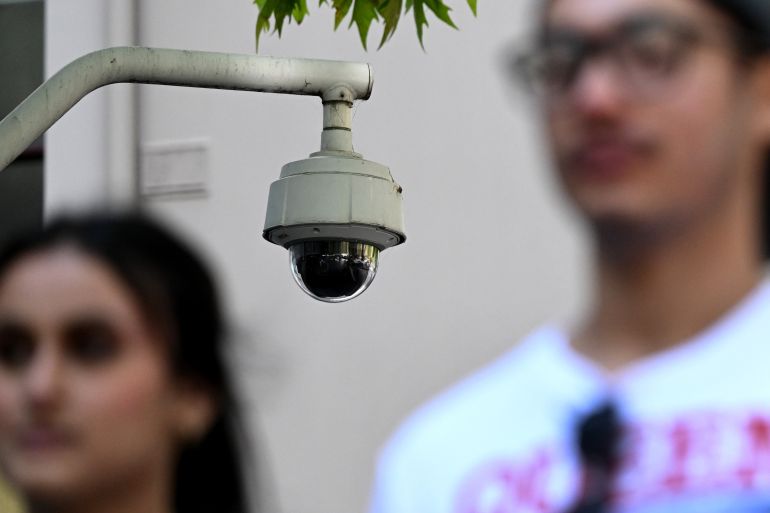 People walk past a security camera in Melbourne on February 9, 2023