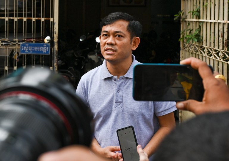 Ith Sothoeuth, director de medios del Centro Camboyano para Medios Independientes (CCIM), hablando con los periodistas sobre la decisión de cerrar VOD.  Lleva una camisa azul pálido y se ve serio y serio.