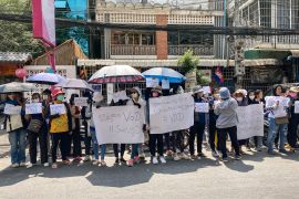 Supporters of VOD gather in Phnom Penh to protest against its closure. They are standing under umbrellas on the street and carrying placards