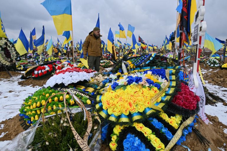 A man walks among graves of Ukrainian soldiers in the "Alley of Glory" of a cemetery in Kharkiv