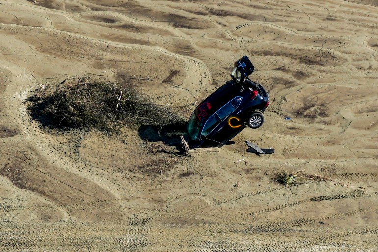 A car is seen stuck in the sand in the aftermath of Cyclone Gabrielle in the Esk Valley near Napier on 18 February, 2023. - New Zealand is under a national state of emergency after Cyclone Gabrielle bore down on its northern coast on February 12. (Photo by STR / AFP) / New Zealand OUT / NEW ZEALAND OUT