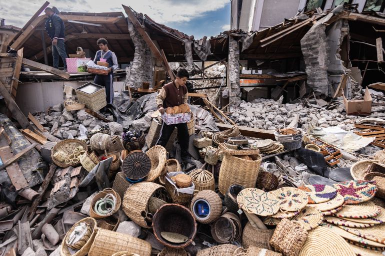 Mustafa Ozdimir (C) helps his family as they collect goods from their collapsed shop in the city of Antakya