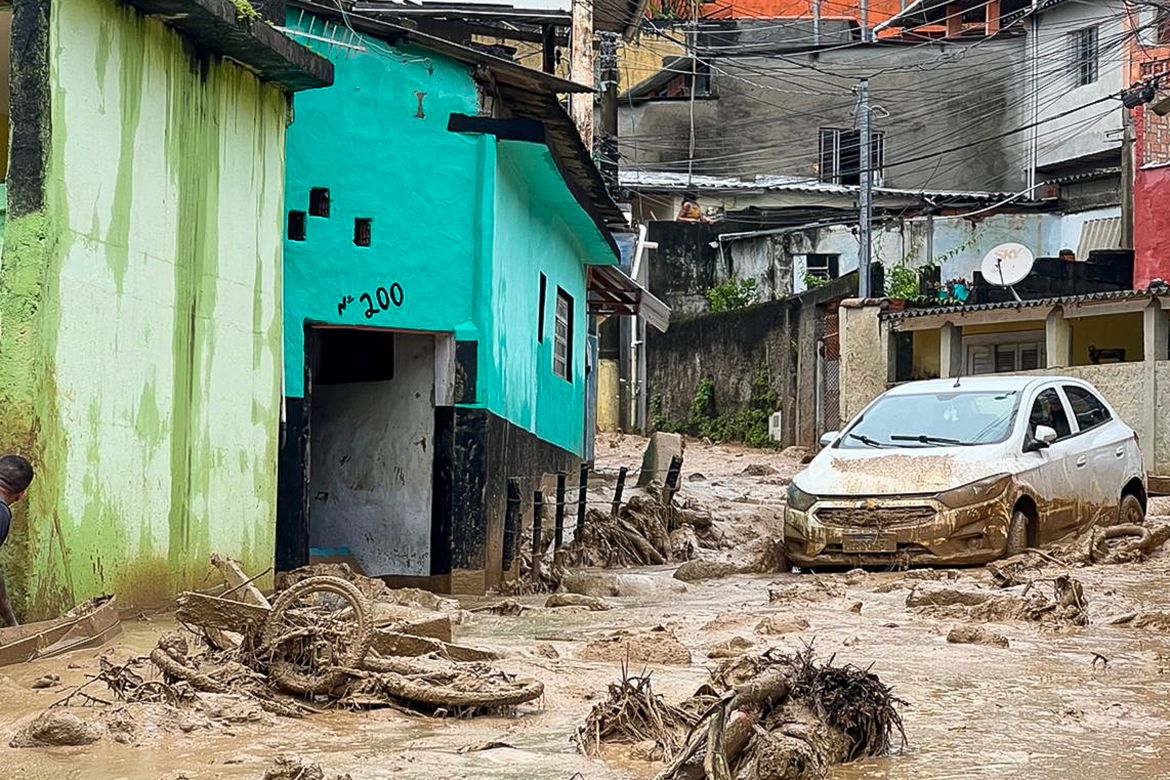 Picture showing damage in Sao Sebastiao. Mud has swept through a street leaving debris including what seems to be a bicycle. There is a white car on the street covered with mud.