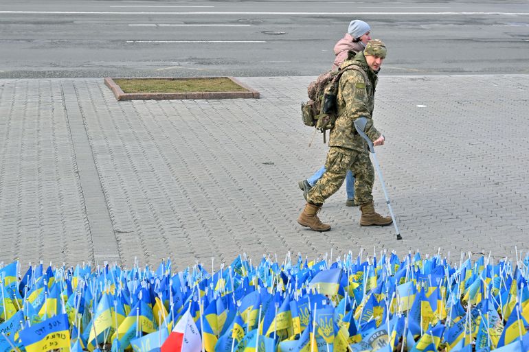 A wounded Ukrainian serviceman and his girlfriend walk past national flags