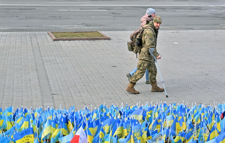 Yaralı bir Ukraynalı asker ve kız arkadaşı ulusal bayrakların önünden geçiyor