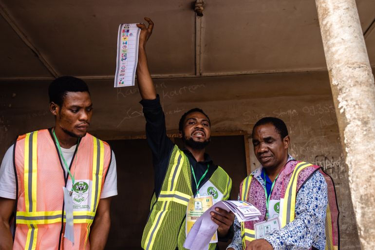 An official holds up a ballot paper with two other election workers at his side.