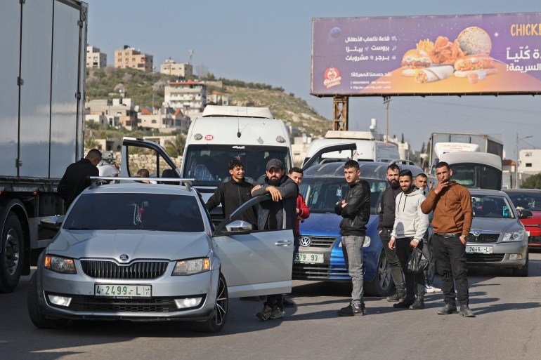 Palestinians wait as Israeli security forces search vehicles at the Hawara checkpoint.