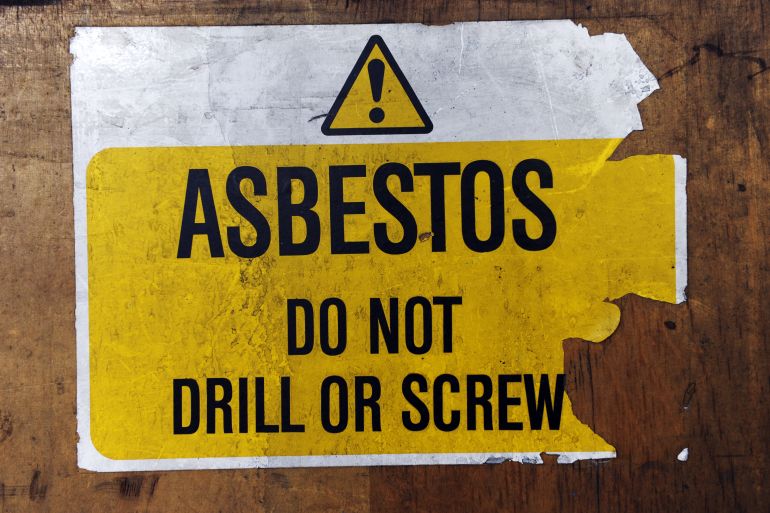 A warning sign reading 'Asbestos, do not drill or screw'
