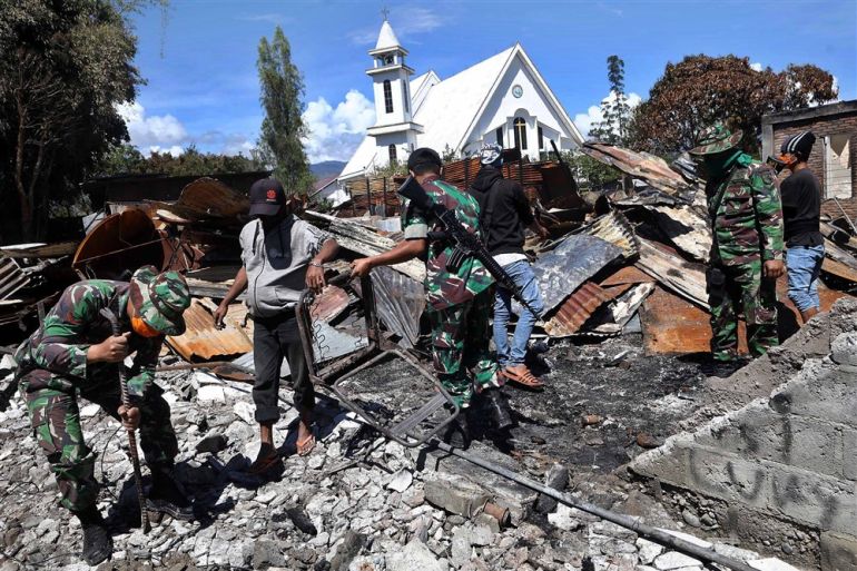 Indonesian security forces and residents clean up the debris of buildings that were torched during riots in Wamena, Papua, Indonesia, in 2019