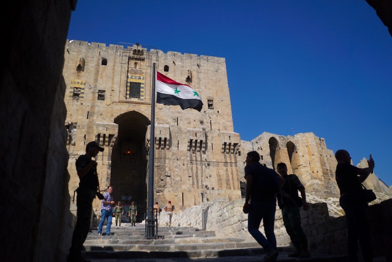 People walk into the Citadel, Aleppo's famous fortress where much of the fierce fighting took place in 2016, in Syria, Tuesday, September 12, 2017. The December 2016 recapture of eastern Aleppo, one of the deadliest episodes of the Syrian civil war, was a historic victory for Assad's forces in the conflict, now entering its seventh year, but it left the area in shambles.  (AP Photo/Nataliya Vasilyeva)