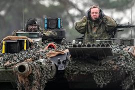 German Defense Minister Boris Pistorius, right, sits on a Leopard 2 tank at the Bundeswehr tank battalion 203 at the Field Marshal Rommel Barracks in Augustdorf, Germany [Martin Meissner/AP]