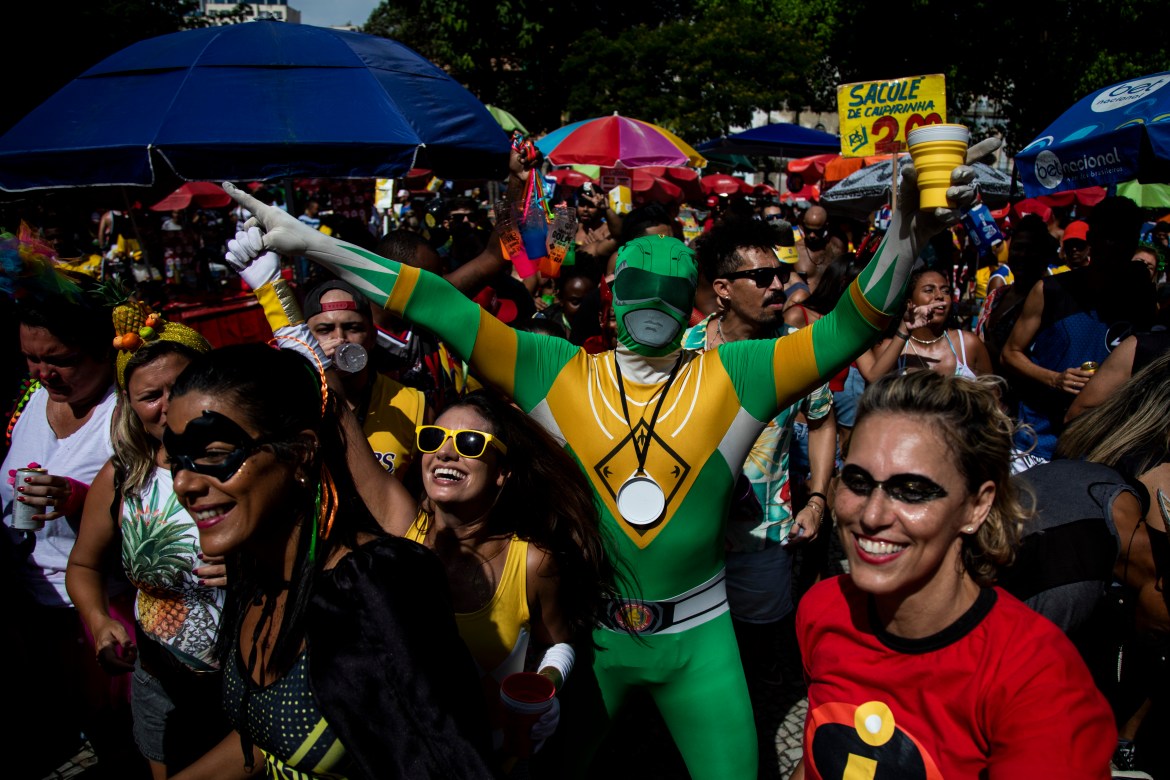 Man dressed as green Power Ranger extends his arms above a crowd