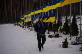 An undertaker walks by the Alley of Heroes at the Irpin Cemetery in Ukraine [Daniel Cole/AP]