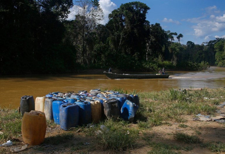 Containers used for mining sit on the bank of the Uraricoera River in Brazil's Amazon