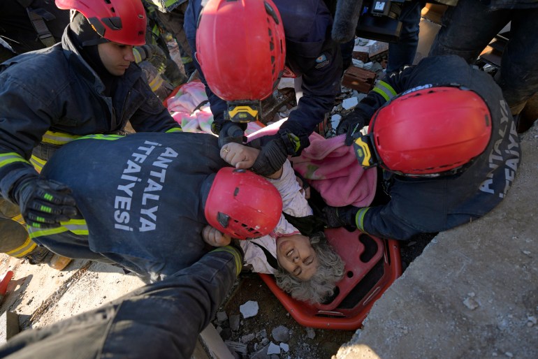 Kurtarma ekipleri, yıkılmış bir binanın enkazından kurtulan birini tahliye ediyor 