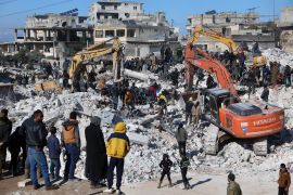 Rescuers and residents search through the rubble of collapsed buildings in the town of Harem near the Turkish border, Idlib province