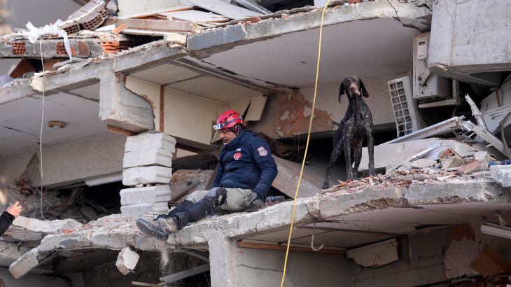 A rescuer with a sniffer dog searches in a destroyed building in Antakya, southeastern Turkey, Friday, Feb. 10, 2023. Rescuers pulled several earthquake survivors from the shattered remnants of buildings Friday, including some who lasted more than 100 hours trapped under crushed concrete after the disaster slammed Turkey and Syria. (AP Photo/Hussein Malla)