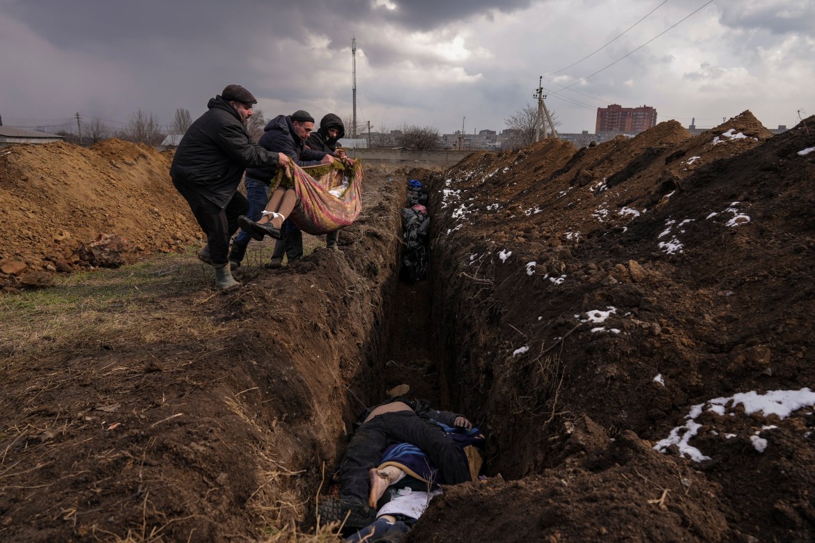 Bodies are placed into a mass grave on the outskirts of Mariupol, Ukraine
