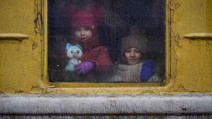 Children look out of the window of an unheated Lviv-bound train, in Kyiv