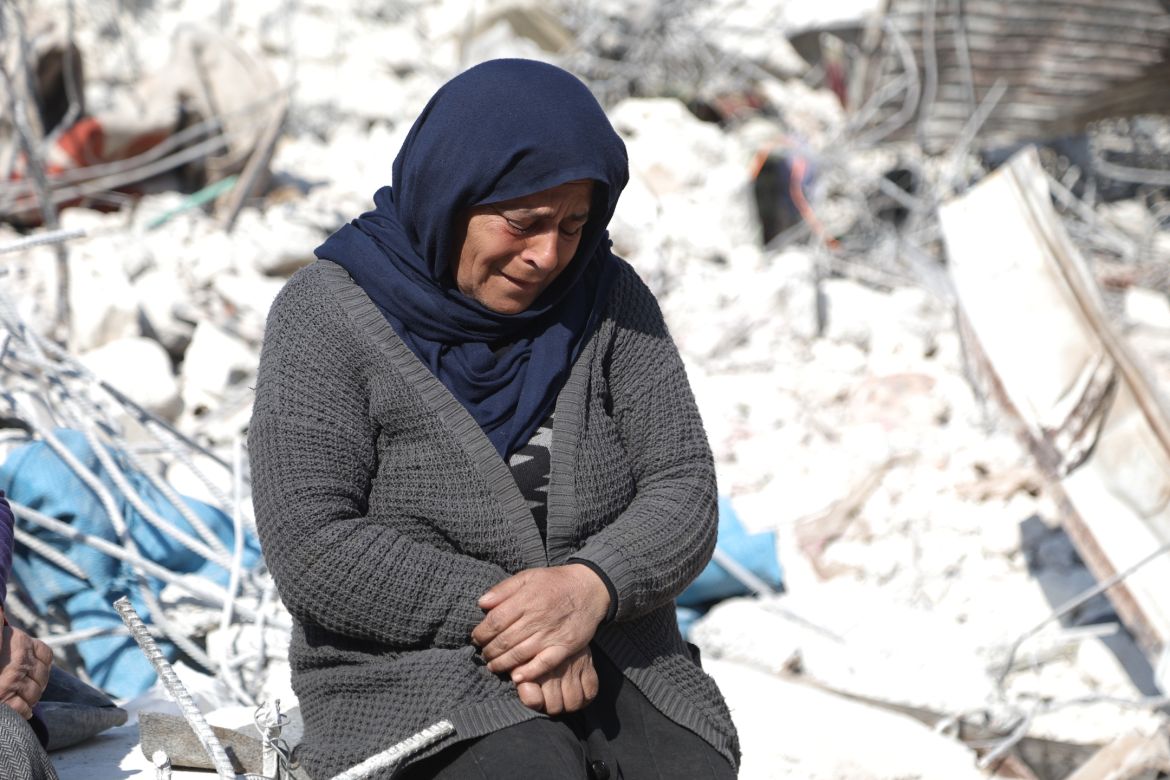 Asmaa' Kousa cries as she sits on top of the rubble of a destroyed building.