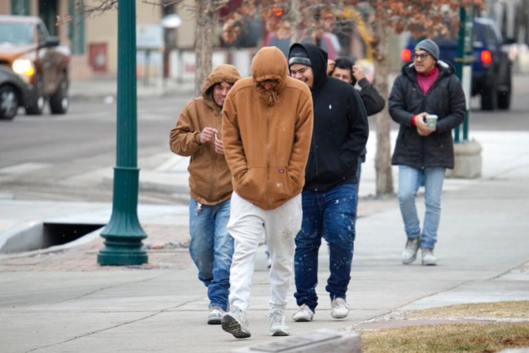 Pedestrians try to stay warm as they walk down the street 