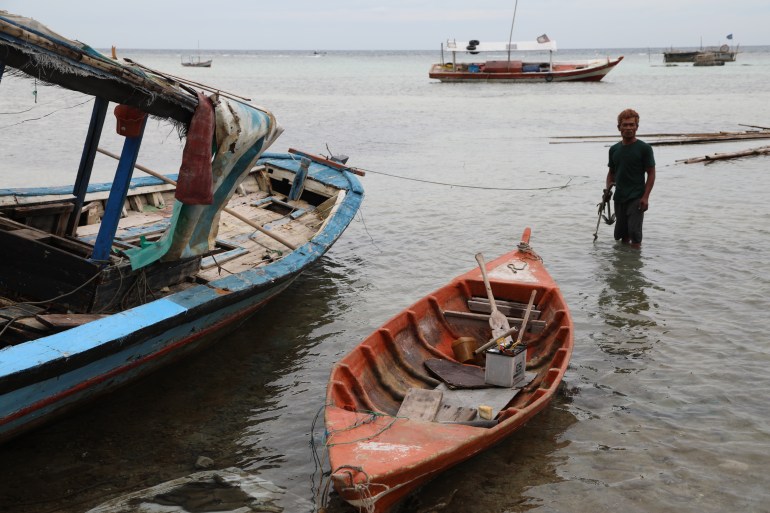 Bateaux de pêche sur l'île de Pari.  Un pêcheur patauge dans l'eau à droite
