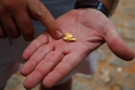A man holds a piece of gold in the palm of his hand