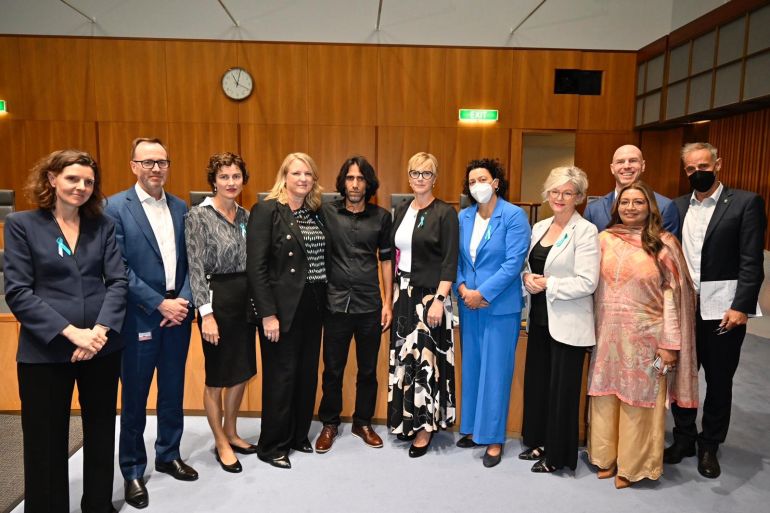 Behrouz Boochani posing with members of parliament in Canberra. He is the centre of the group and dressed in black