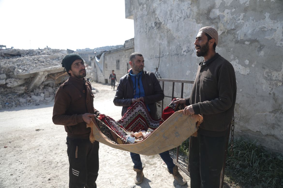 THree men hold a small carpet with donations on it
