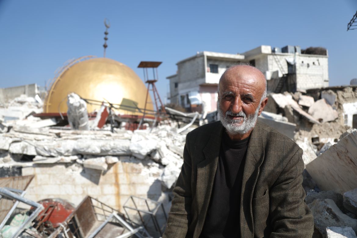 Mahmoud Aref Nadaf sits on the rubble in front of the fallen Maland mosque