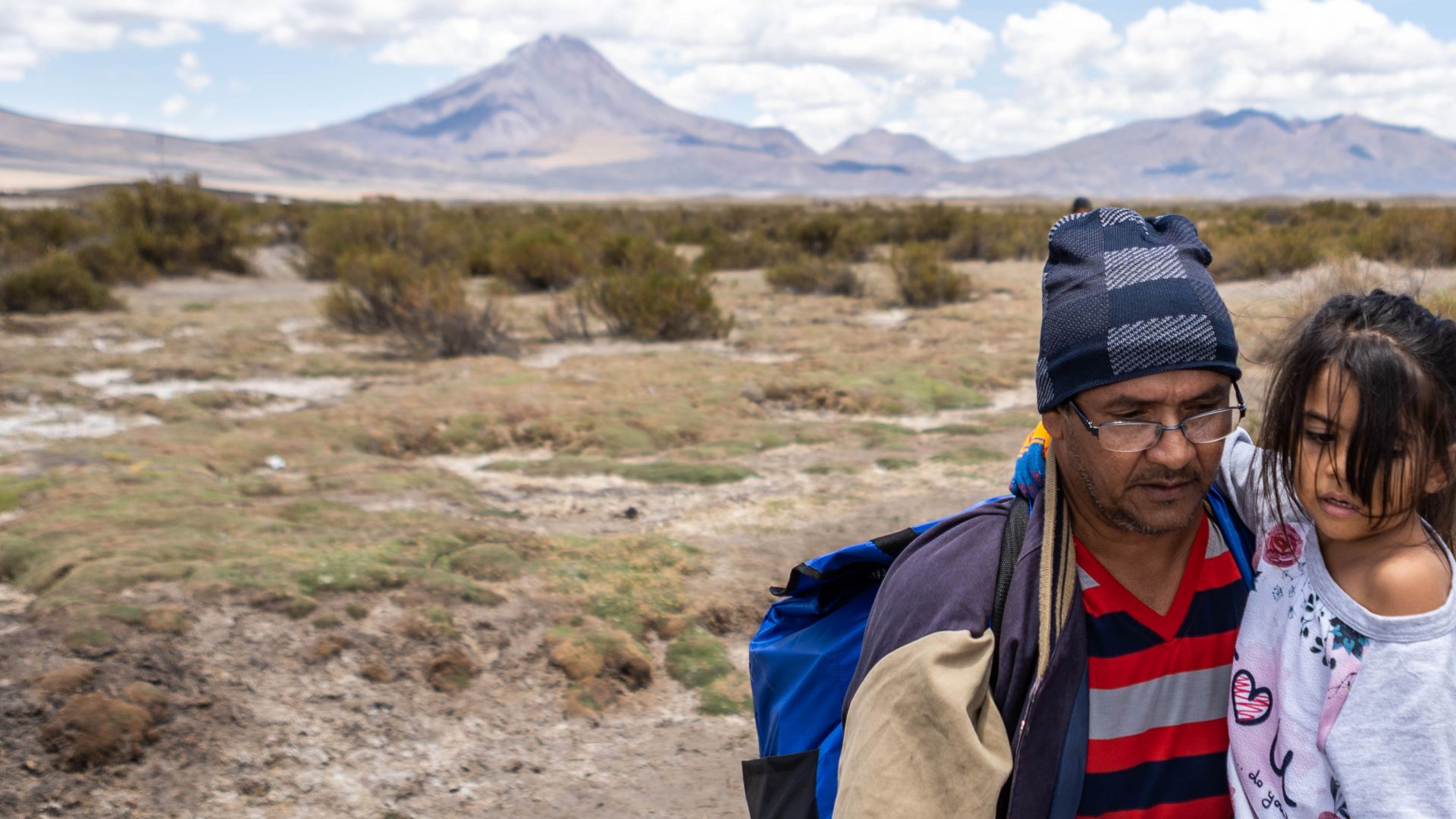 A man carries a 5-year-old girl, Allyson, across the Altiplano highlands.