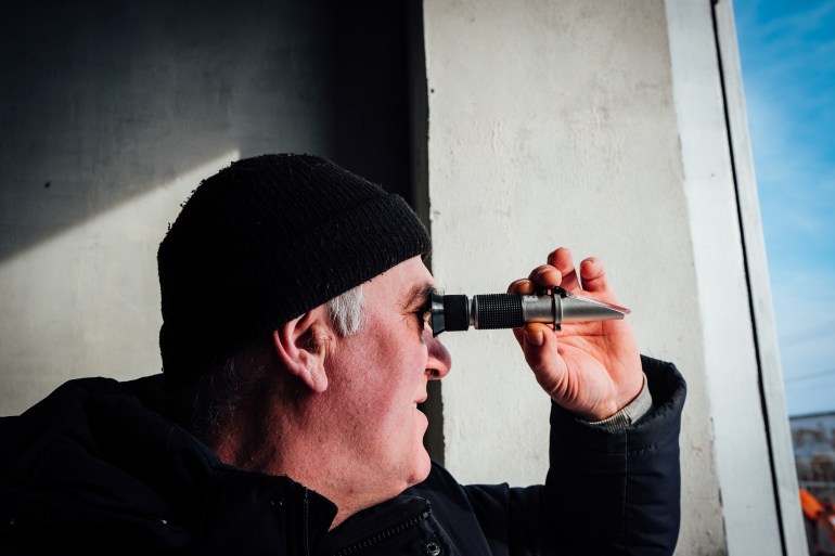 A photo of Roman Danyliak using a refractometer to check the sugar content of his wine.